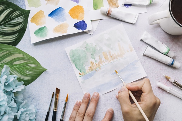 Mani che colorano con gli acquarelli con sfumature chiare.