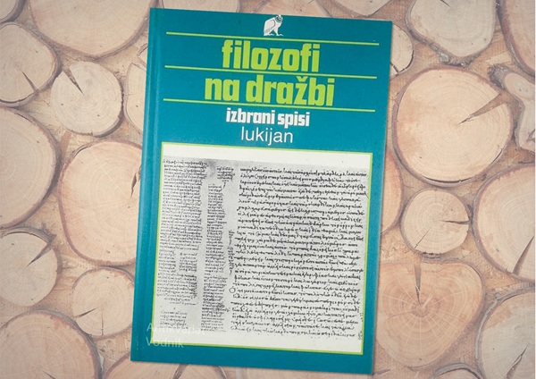 Zelenomodra naslovnica knjige na leseni podlagi.